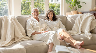  Two adults wearing linen and bamboo robes relax in bright summer living room