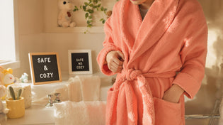  Parent helping child with safe, cozy bathrobe in home bathroom