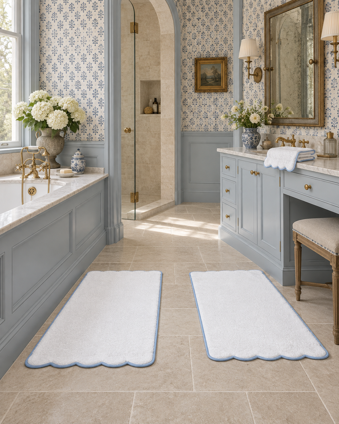 Folded white towels beside two scalloped bath mats with light blue piping