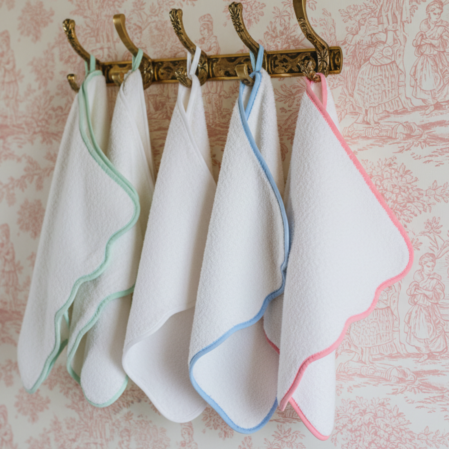 White scallop-edged bath towels in mint, blue, and pink piping hung on brass hooks for spa-worthy softness - Lotus Linen