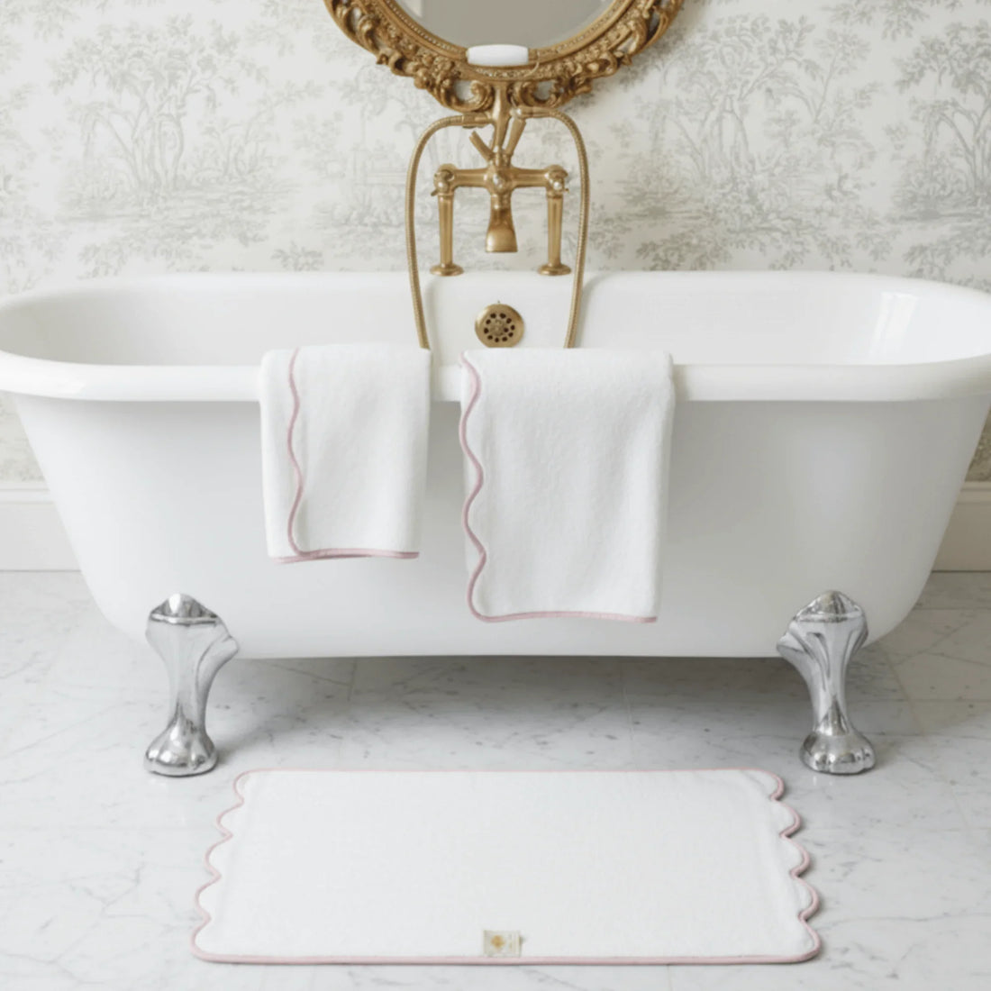 White scalloped-edge bath towels draped over clawfoot tub with matching bath mat in elegant bathroom - Lotus Linen