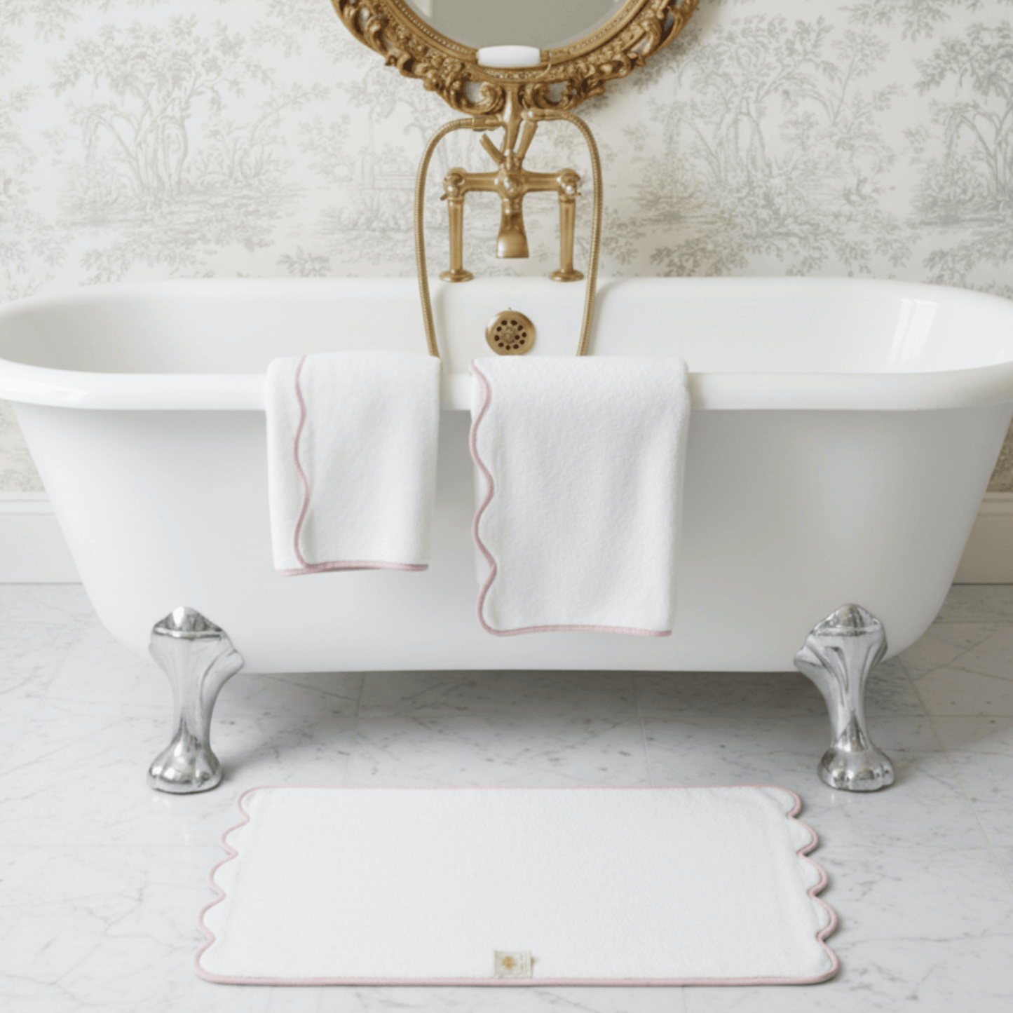 White scalloped-edge bath towels draped over clawfoot tub with matching bath mat in elegant bathroom - Lotus Linen