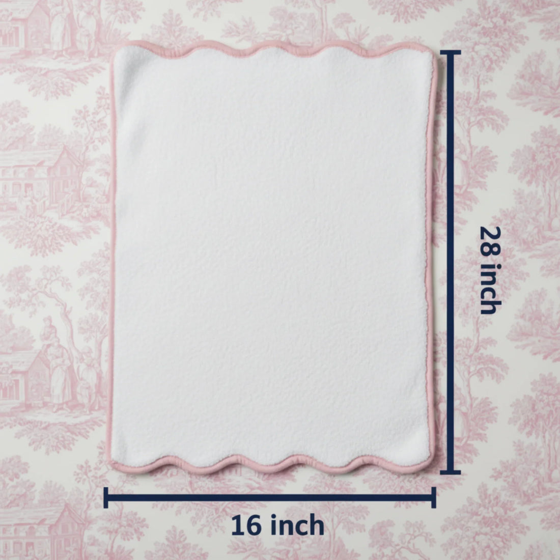 White bath mat with pink border on a pink floral background, measured at 16x28 inches.