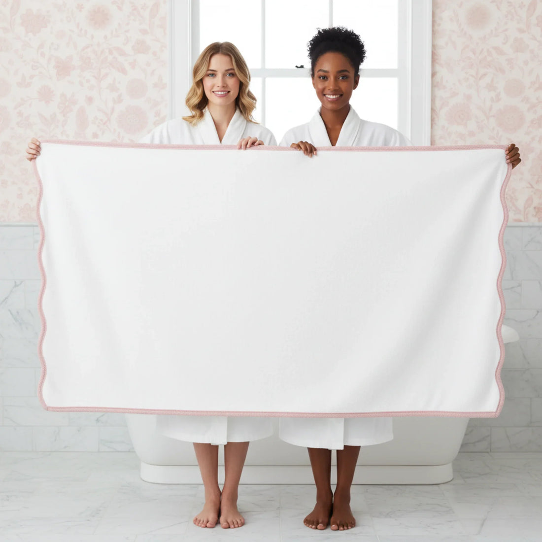 Two women in robes holding an oversized white bath sheet with pink scallop piping for everyday luxury and spa-quality comfort - Lotus Linen