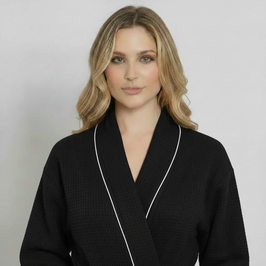 Woman in black waffle bathrobe with white piping for effortless spa-style relaxation at home - Lotus Linen