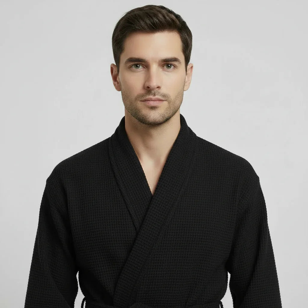 Man in black waffle spa bathrobe enjoying lightweight breathable comfort after a relaxing bath - Lotus Linen