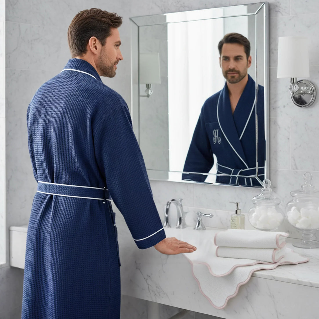 Man in navy waffle piping robe with white trim enjoying spa-quality comfort at marble vanity - Lotus Linen